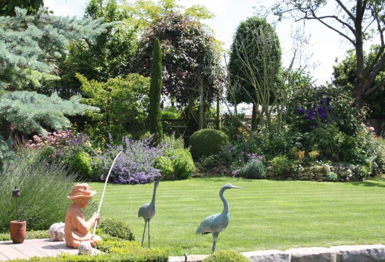 Jardin fleuri avec statues d'oiseaux et un pêcheur